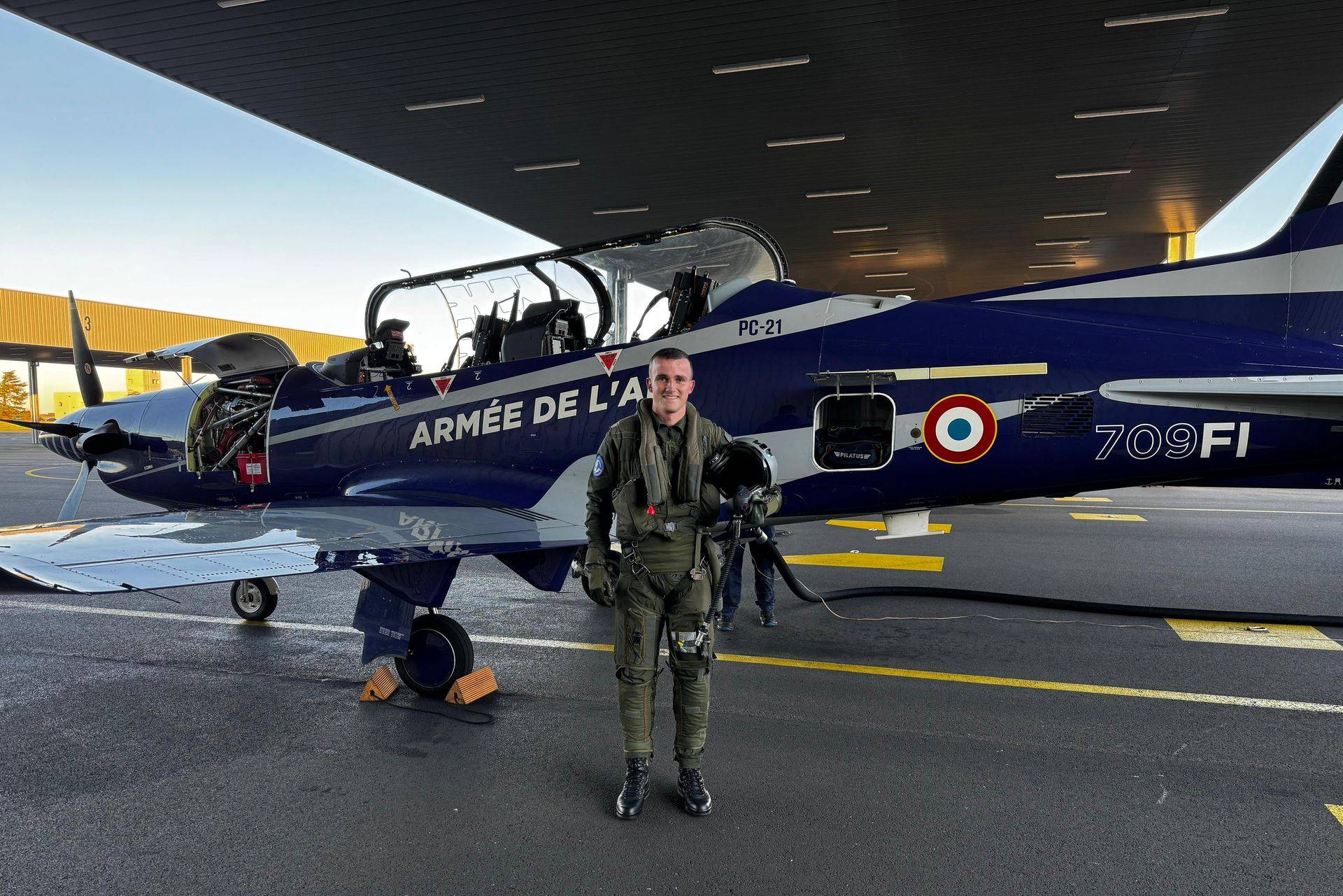 Élève officier sous contrat de la promotion OSC 24 Charlie en stage à l'école de l'aviation de chasse de Cognac, posant devant un Pilatus PC-21